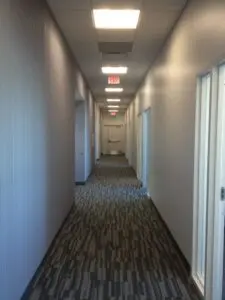 A hallway with many doors and lights on the ceiling.